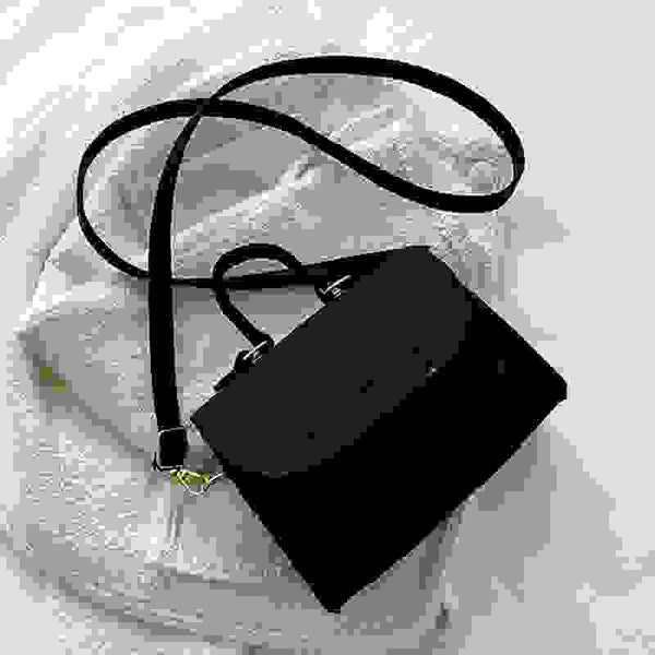 Black leather small square single shoulder bag with top handle and crossbody strap, ideal for versatile everyday wear.